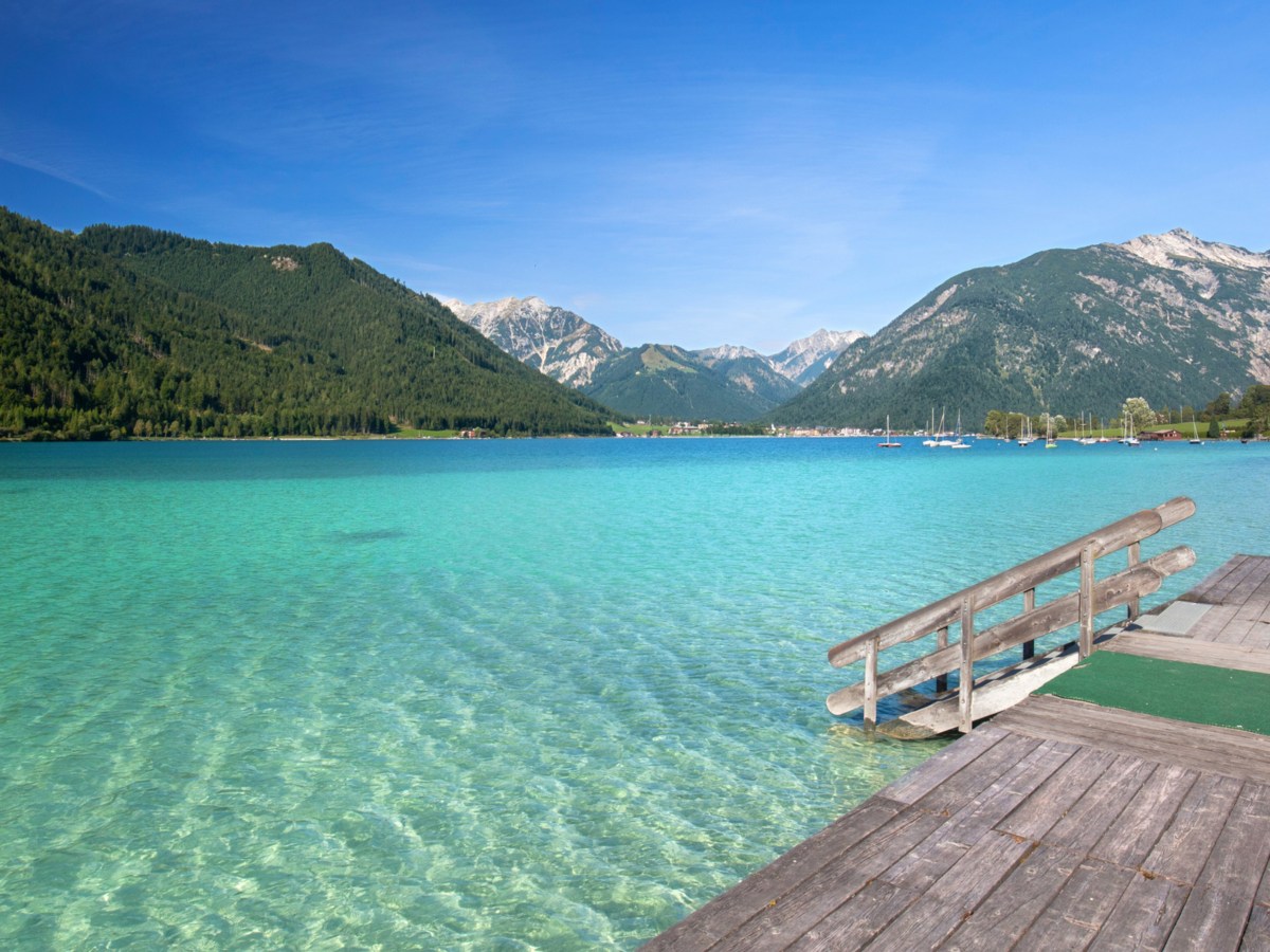 Badesee mit Steg umgeben von Bergen