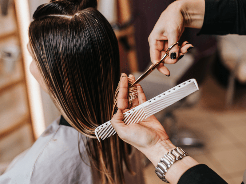 Frau beim Friseur, die die Haare geschnitten bekommt.