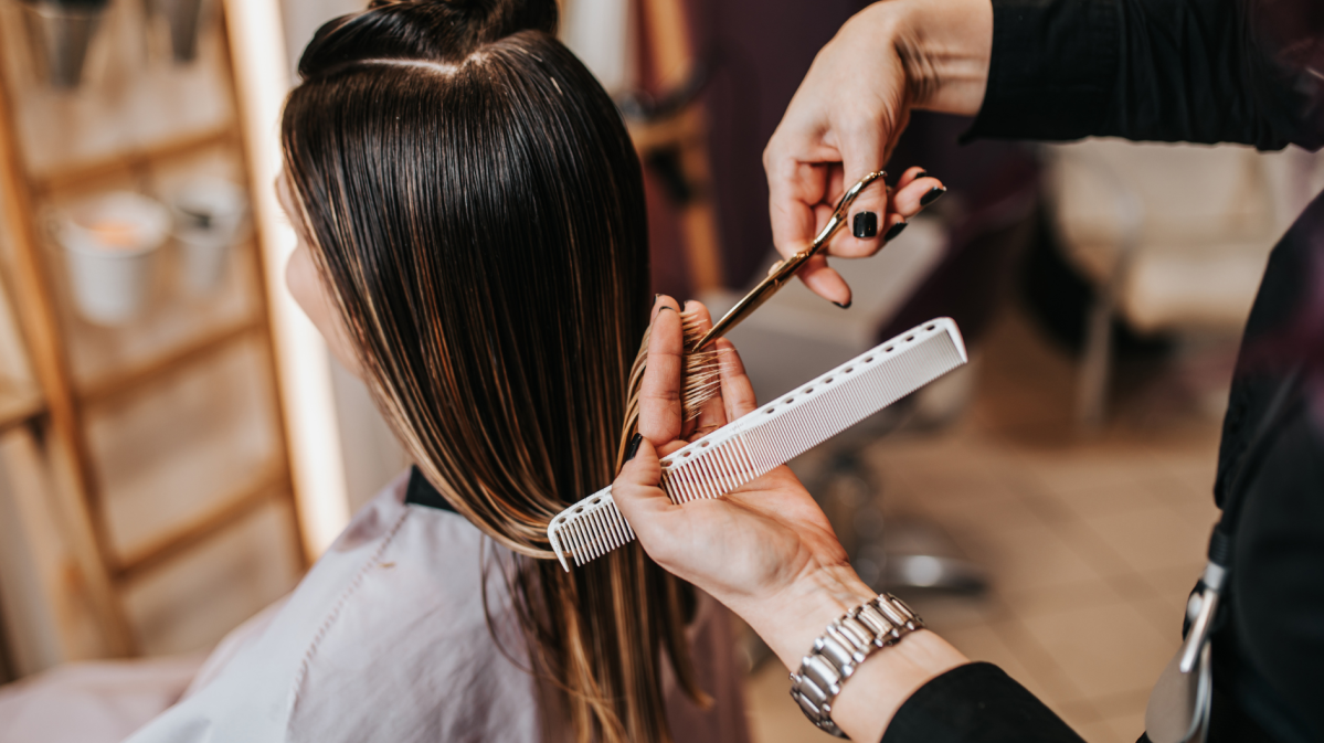 Frau beim Friseur, die die Haare geschnitten bekommt.