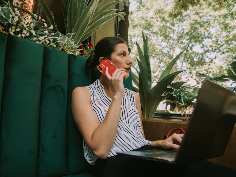 Business-Woman sitzt am Laptop und telefoniert.