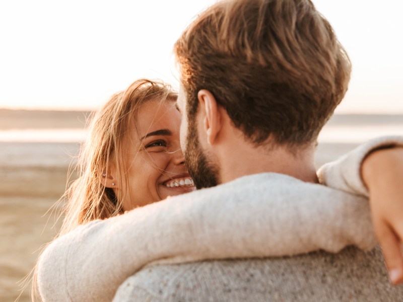 Frau und Mann liegen sich in den Armen am Strand.