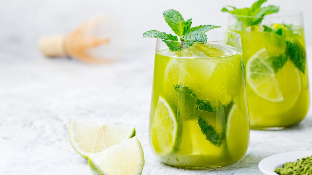 Matcha Lemonade mit Minze und Limettenscheiben in einem kurzen Glas.