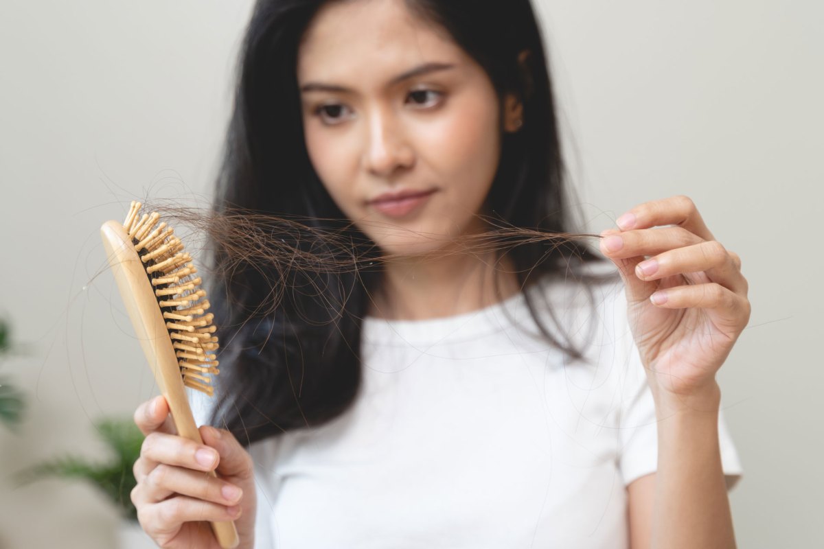 Frau, die Haarbüschel aus der Bürste zieht.