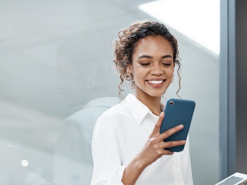 Frau hat ein Handy auf der Arbeit in der Hand.