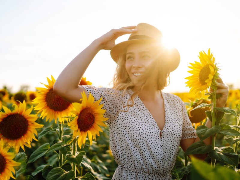 Frau auf einem Feld voller Sonnenblumen.