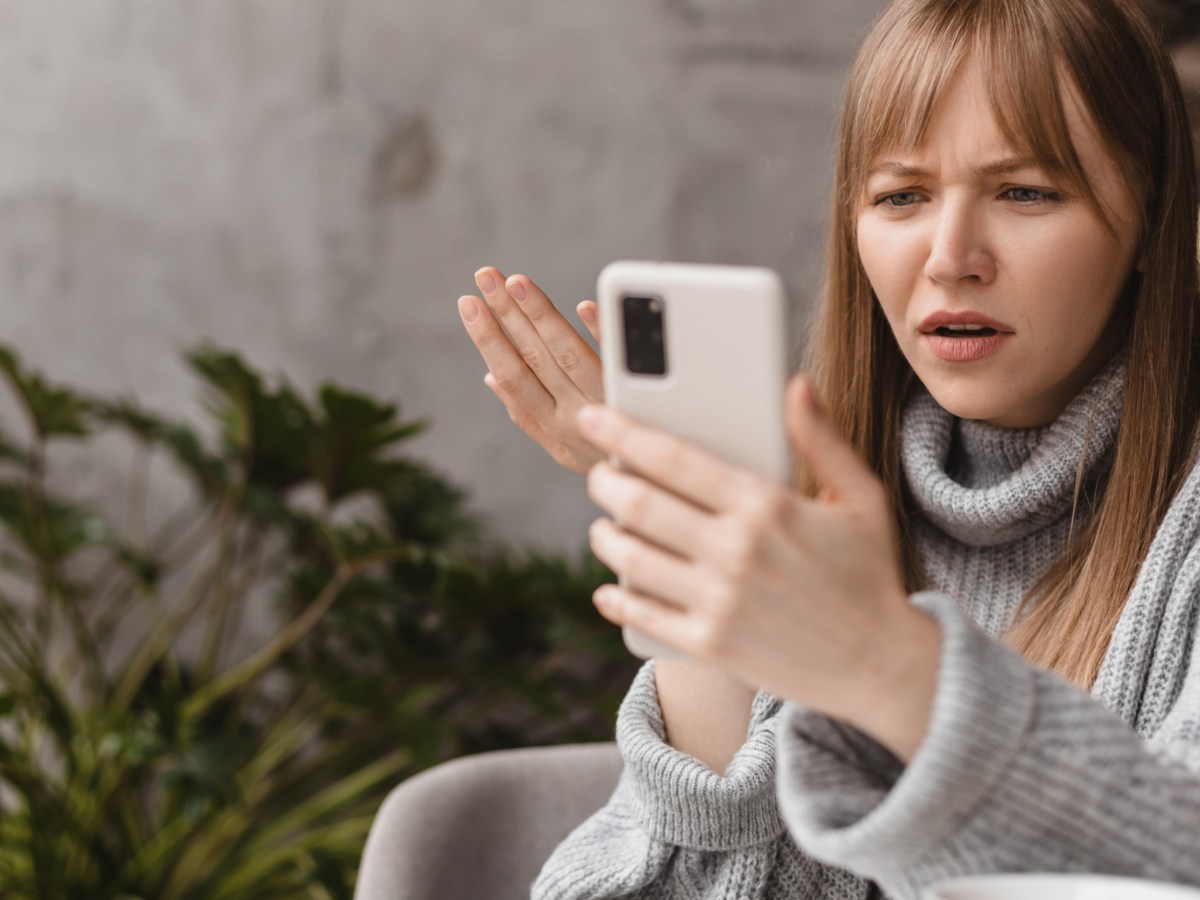 Frau schaut wütend auf ihr Handy.