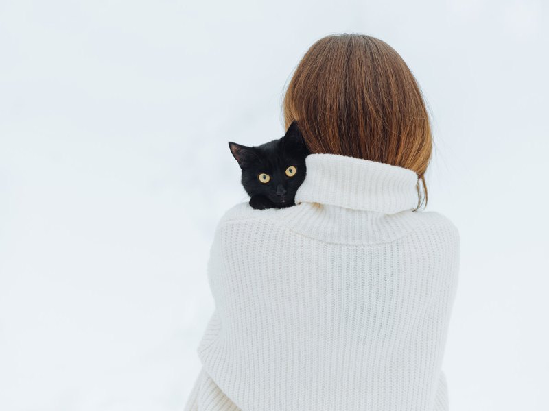 Frau hält eine schwarze Katze auf dem Arm