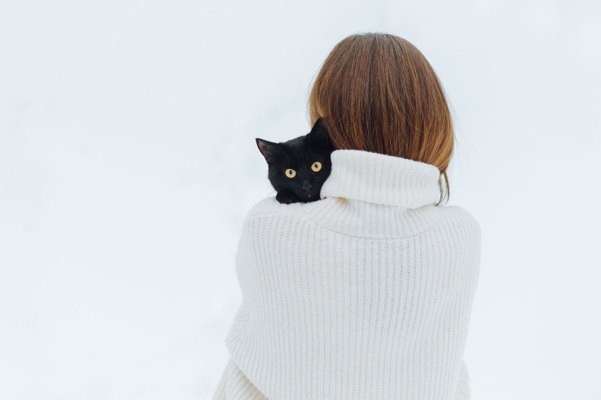 Frau hält eine schwarze Katze auf dem Arm