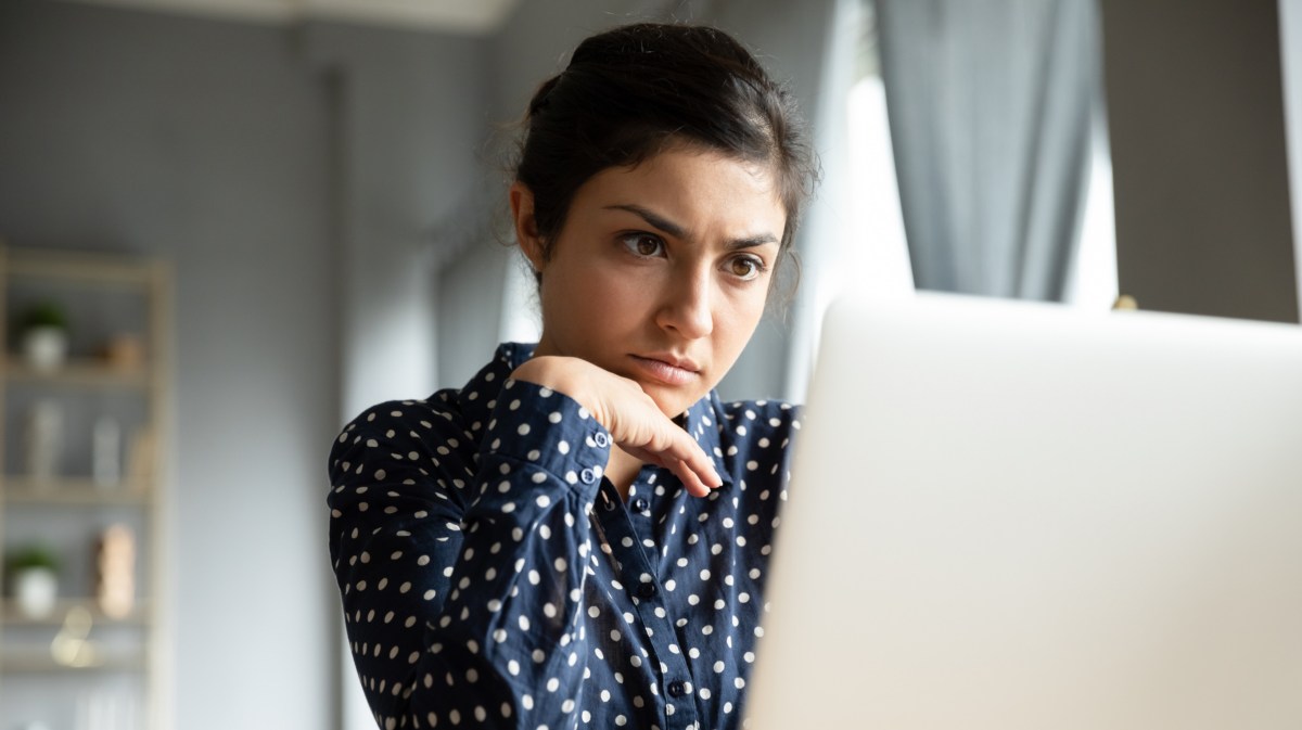 Frau, die mürrisch und genervt auf ihren Computer Bildschirm schaut