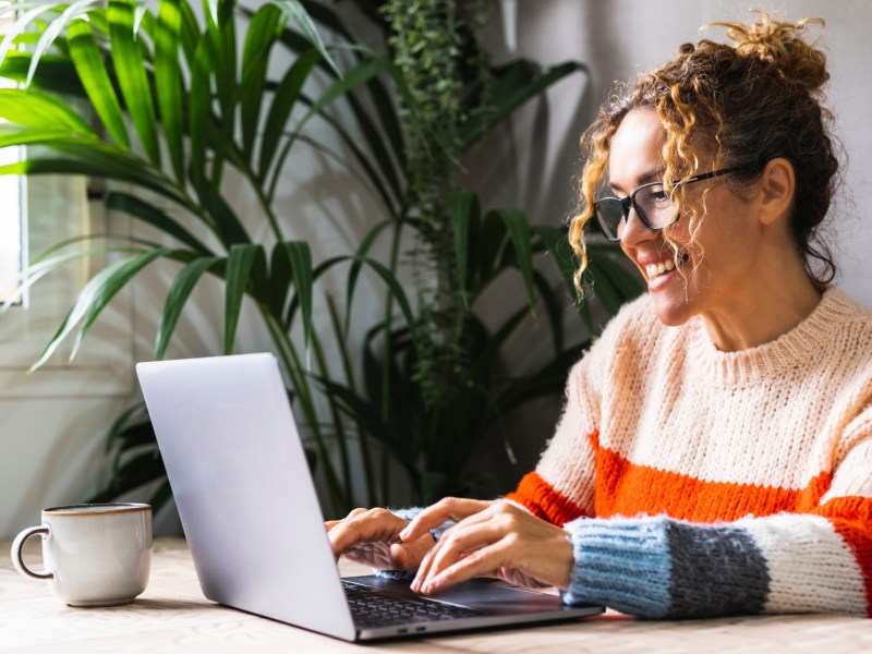 Frau sitzt am Schreibtisch mit ihrem Laptop.