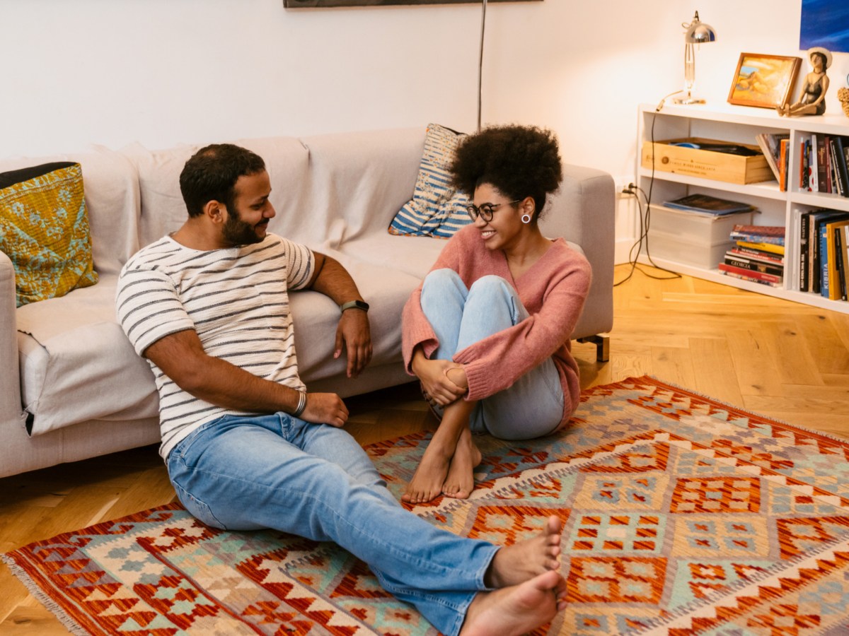 Frau und Mann auf dem Boden vor dem Sofa, die gemeinsam reden und lachen