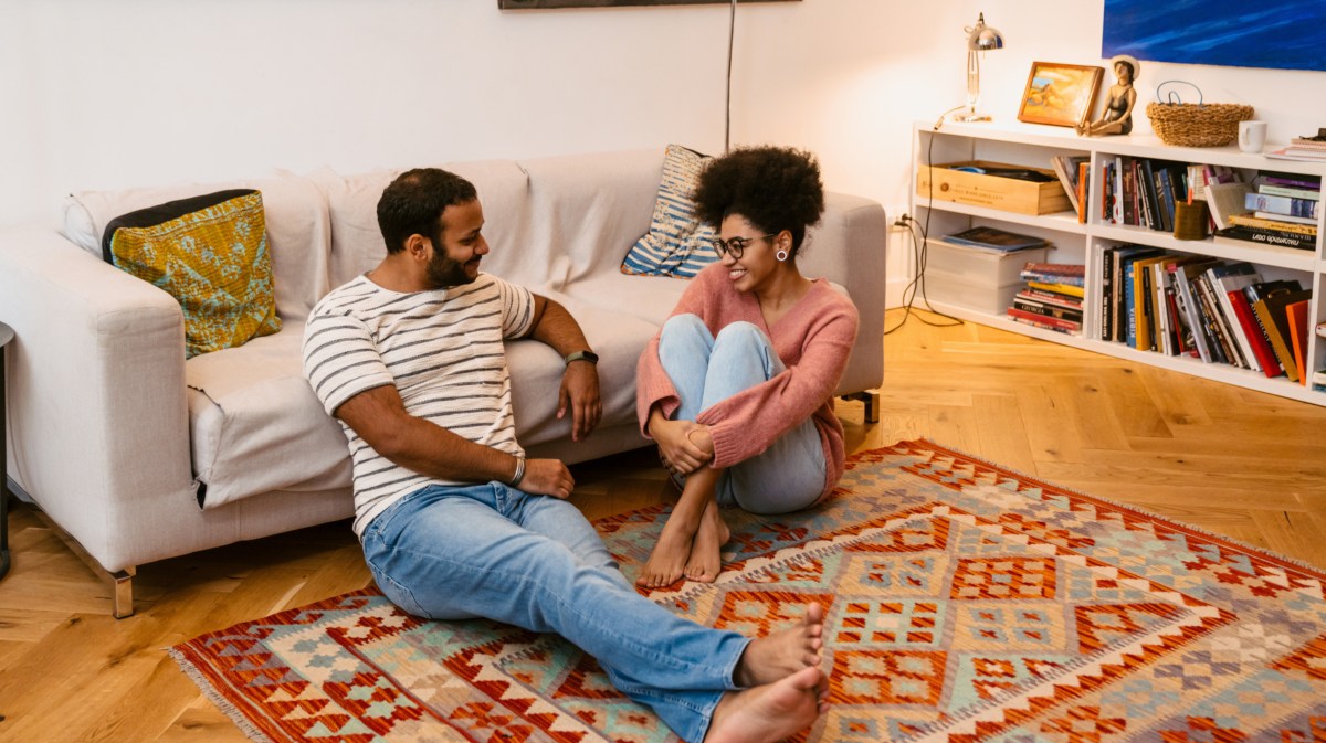 Frau und Mann auf dem Boden vor dem Sofa, die gemeinsam reden und lachen