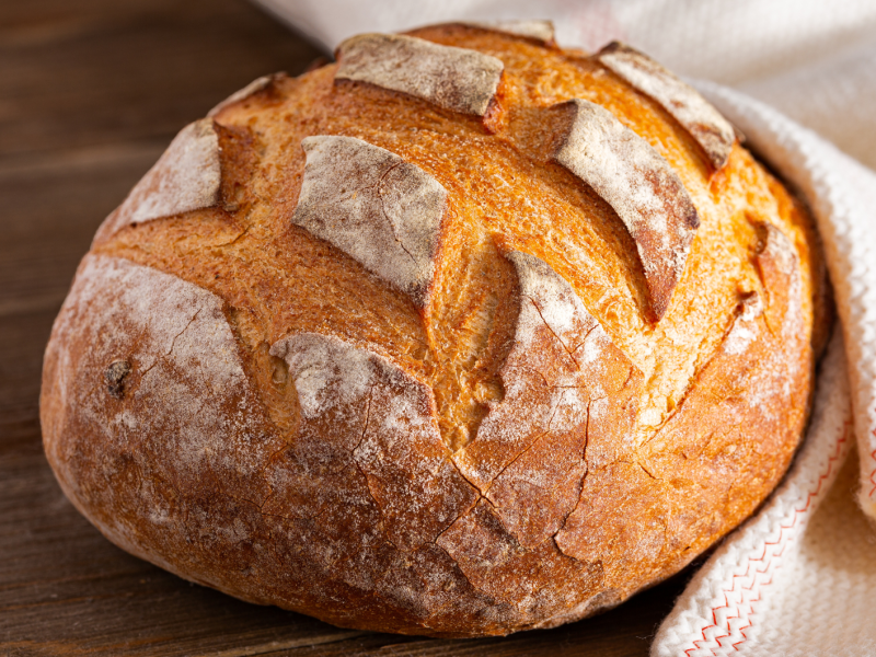 Brot in einem weißen Tuch auf Holz.