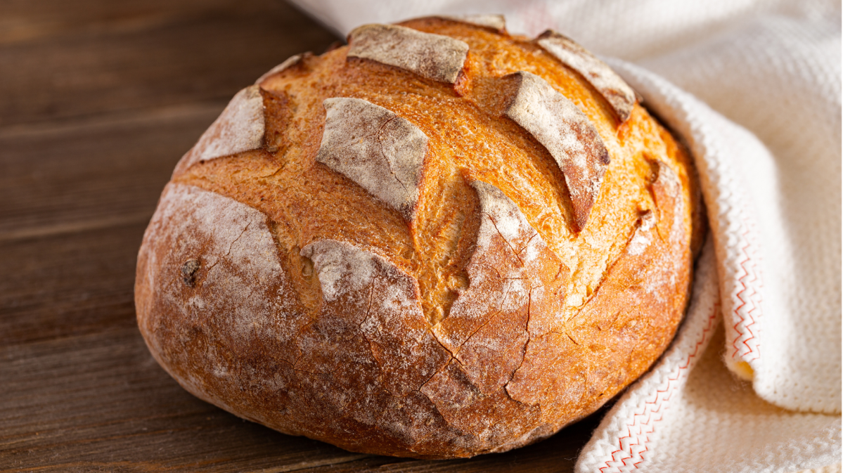 Brot in einem weißen Tuch auf Holz.