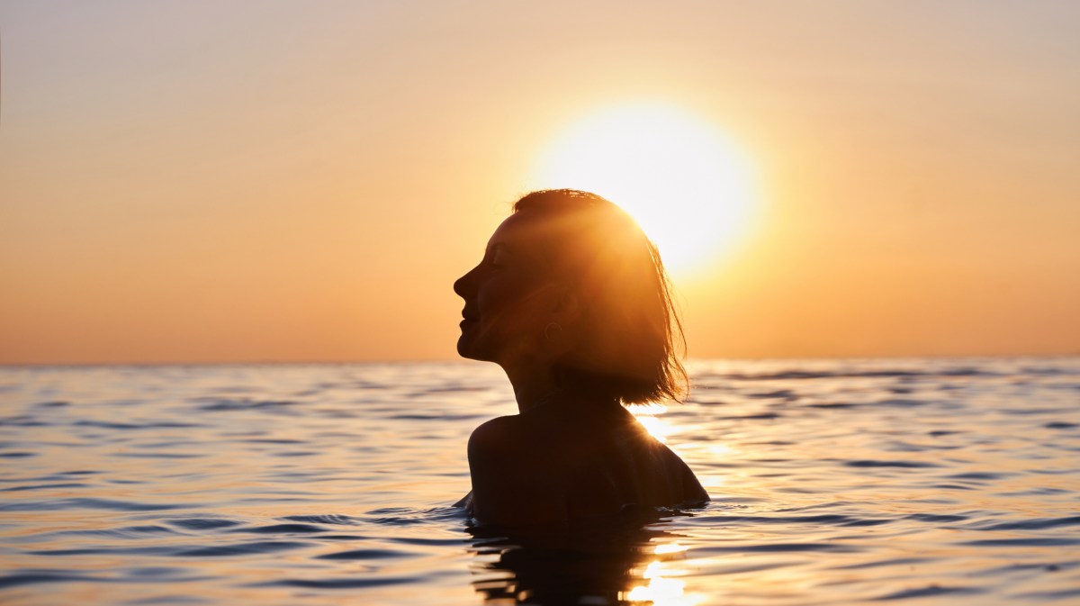 Frau im Meer im Sonnenuntergang