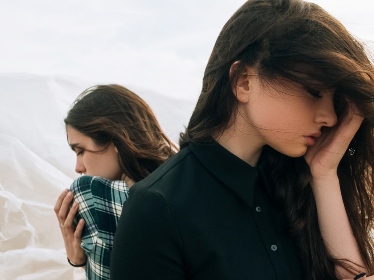 Zwei Frauen, die im Wind draußen stehen und traurig in die jeweils andere Richtung schauen