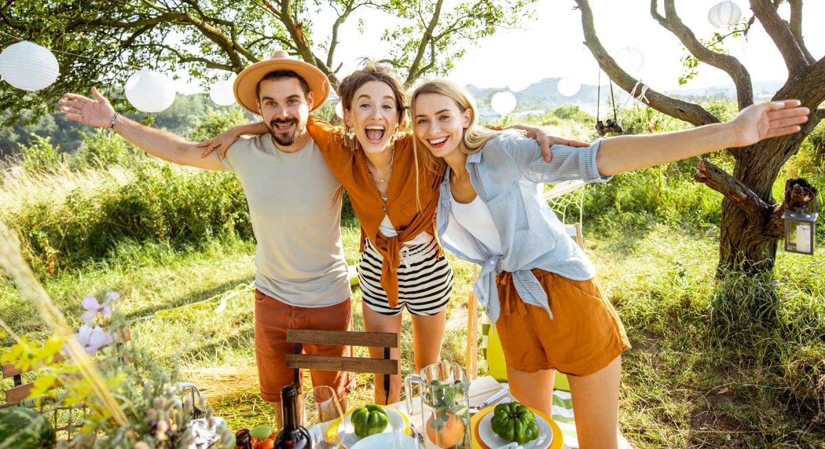 Zwei Frauen in ein Mann lachen ausgelassen vor Wiese