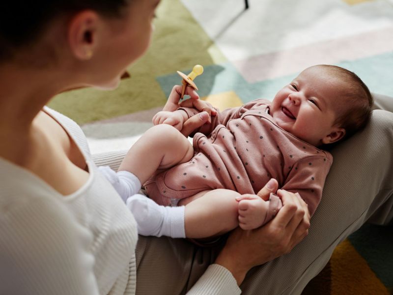 Lachendes Baby auf dem Schoß der Mutter