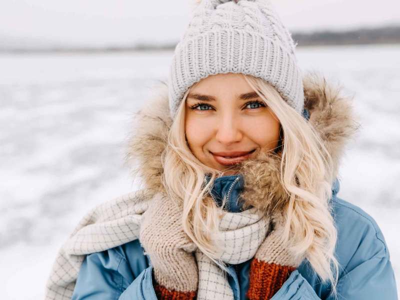 Junge blonde Frau mit Mütze im Schnee.