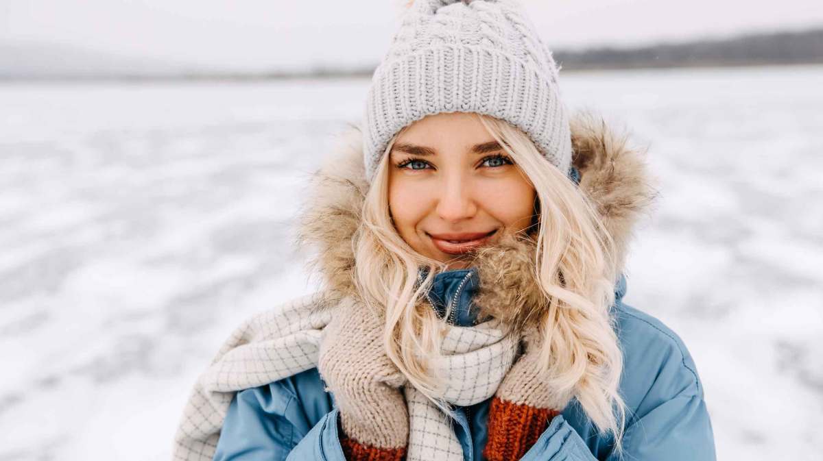 Junge blonde Frau mit Mütze im Schnee.