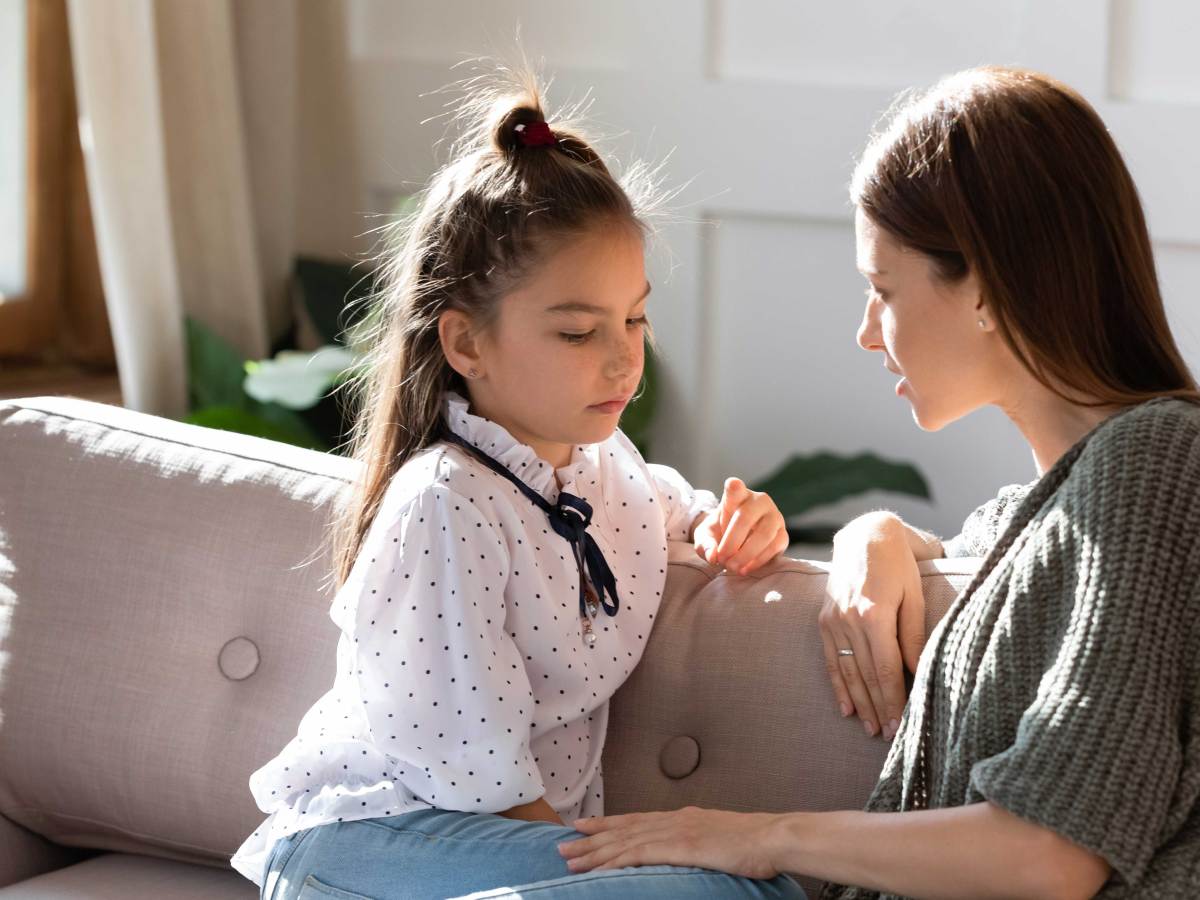 Mutter und Tochter sitzen auf dem Sofa und unterhalten sich ernst.