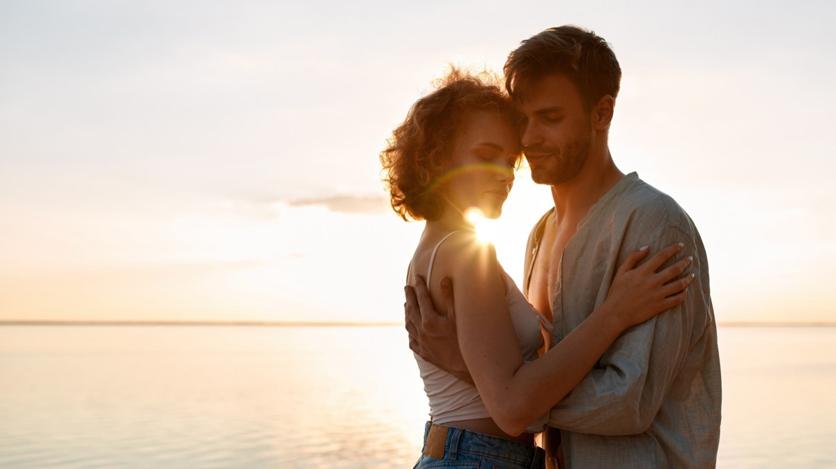 Mann und Frau im Sonnenuntergang, die sich gegenseitig umarmen