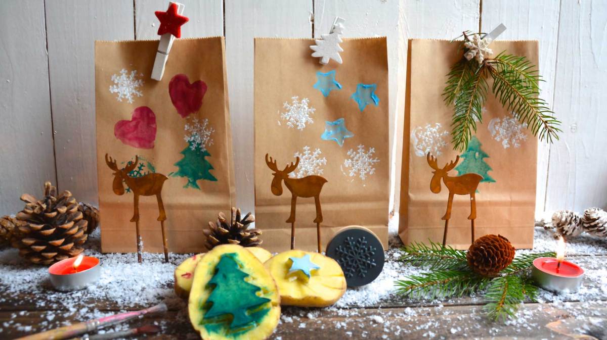 Drei kleine Geschenktüten, die per Kartoffeldruck von Kindern gestaltet wurden. Im Vordergrund liegt noch eine geschnitzte Kartoffel.