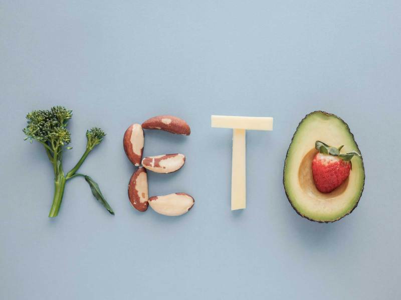 Keto Wort aus Ketogenic Diät, Low-Carb, ketogene Ernährung auf blauem Pastell Hintergrund