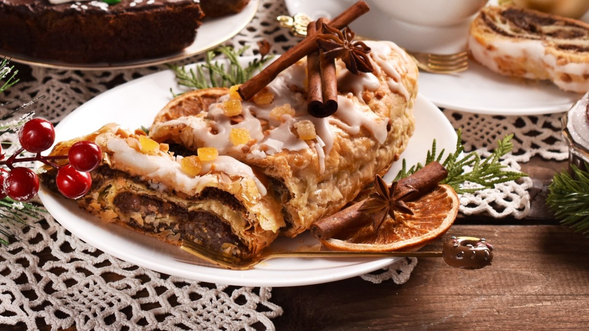 Der Schokoladen-Stollen auf einem weißen Teller mit viel weihnachtlicher Deko drum herum.