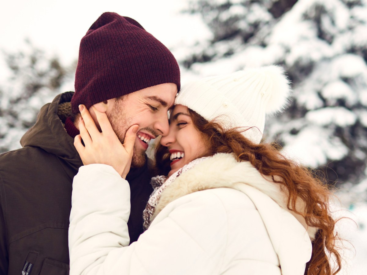 Frau und Mann küssen sich im Schnee.