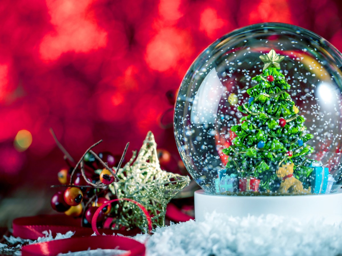 Eine Schneekugel mit einem Tannenbaum und Weihnachtsdeko auf einem Tisch dekoriert