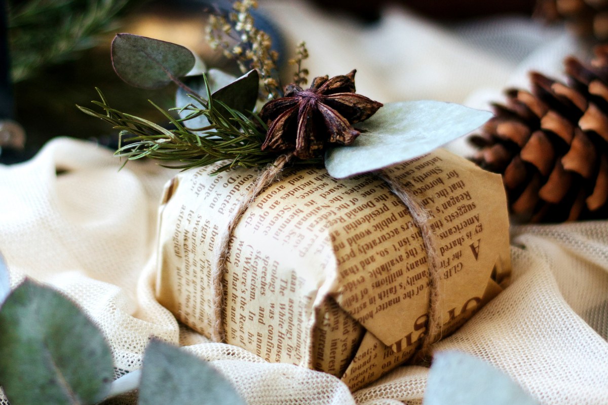 Ein Weihnachtsgeschenk eingepackt in Zeitungspapier und mit Kordel und Naturmaterialien dekoriert.