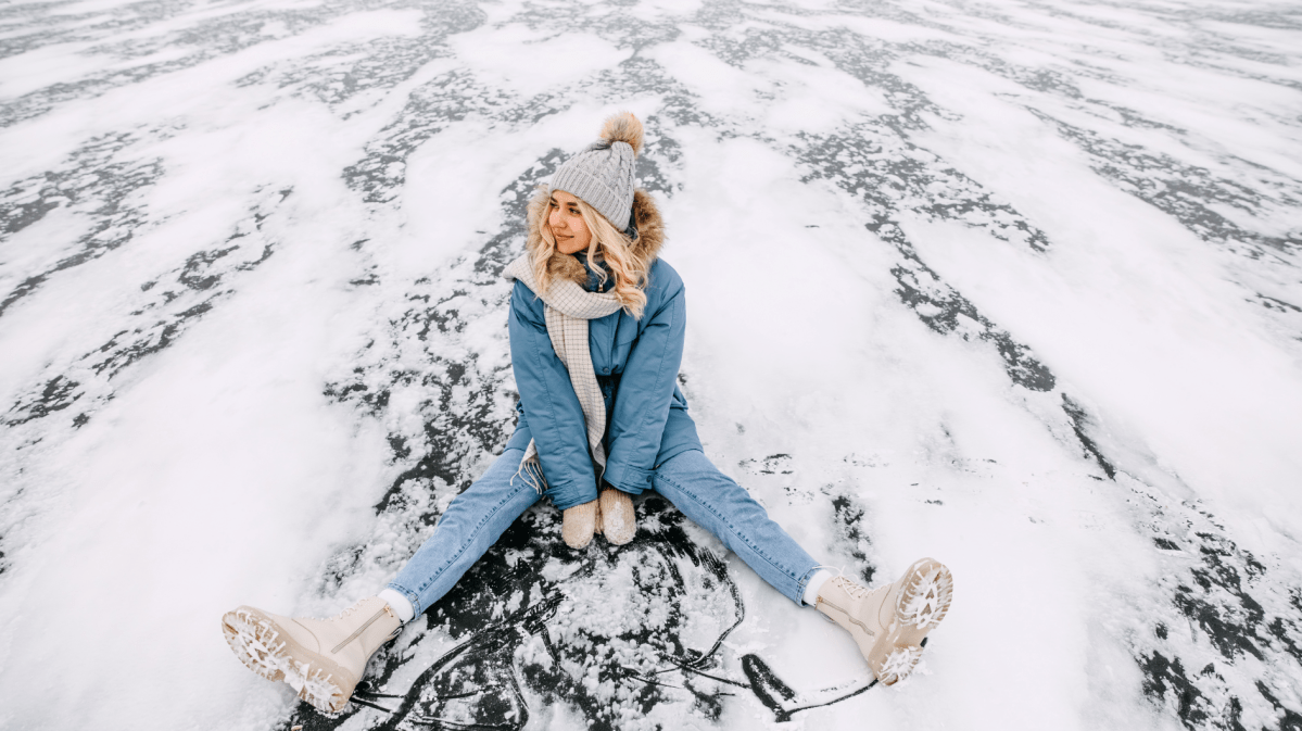 Frau im Schnee auf einer Eisplatte die lächelt und zur Seite schaut