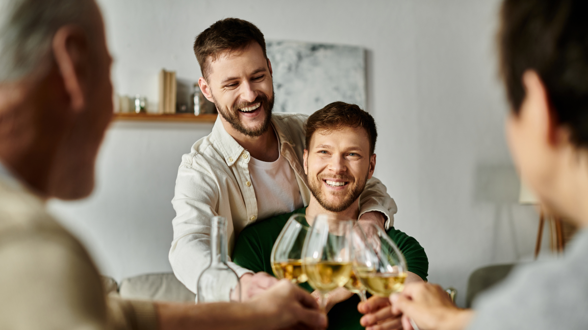 Zwei Männer, die mit einem Weinglas mit zwei anderen Menschen anstoßen.