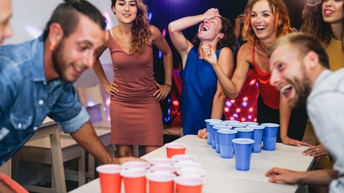 Gruppe von jungen Leuten spielen Beer Pong auf Party.