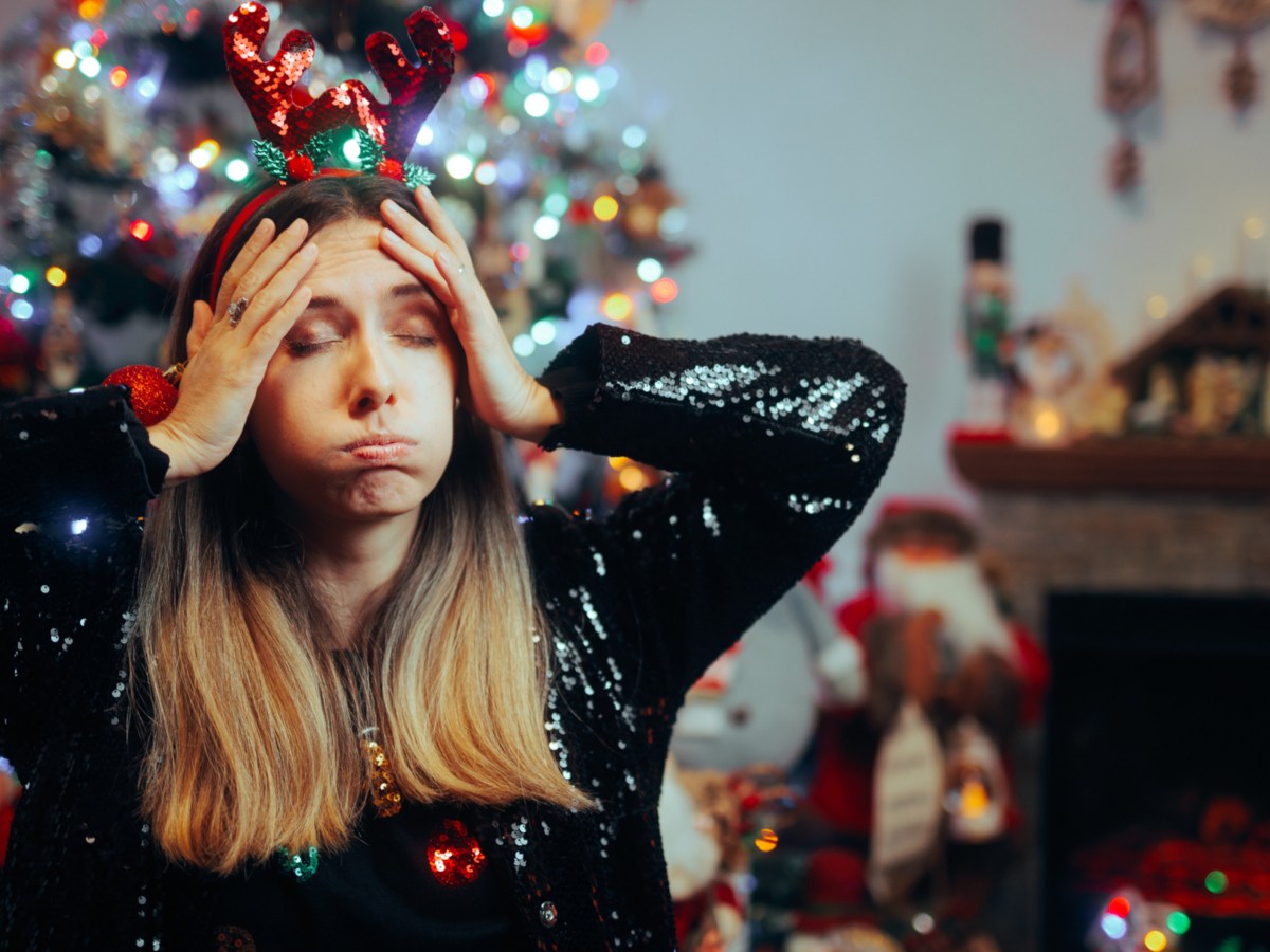 Frau sieht erschöpft aus unter Weihnachtsbaum.