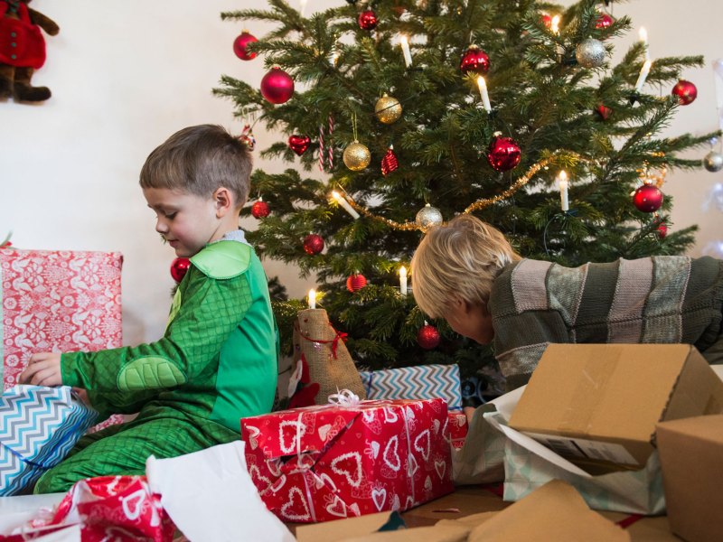 Weihnachtsgeschenke und zwei jüngere Jungen vor Weihnachtsbaum