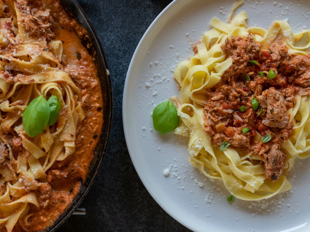 Tagliatelle mit Tomaten-Thunfisch-Soße auf weißem Teller.