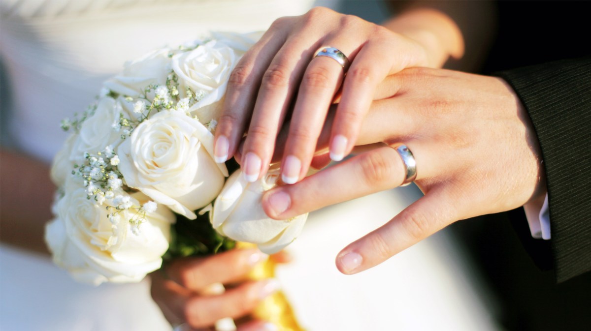 Frau und Mann, die sich das Ja-Wort gegeben haben und jetzt ihre Hochzeitsringe zeigen