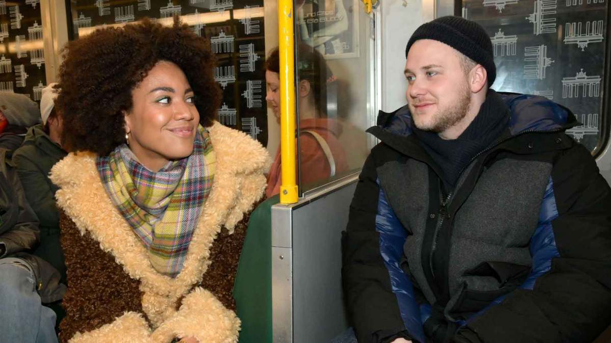 GZSZ-Figuren Flo Kästner, gespielt von Pauline Afaja und Jonas Seefeld, gespielt von Felix van Deventer sitzen in der Berliner U-Bahn.