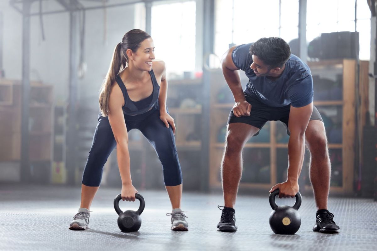 Mann und Frau heben Hanteln beim Sport.