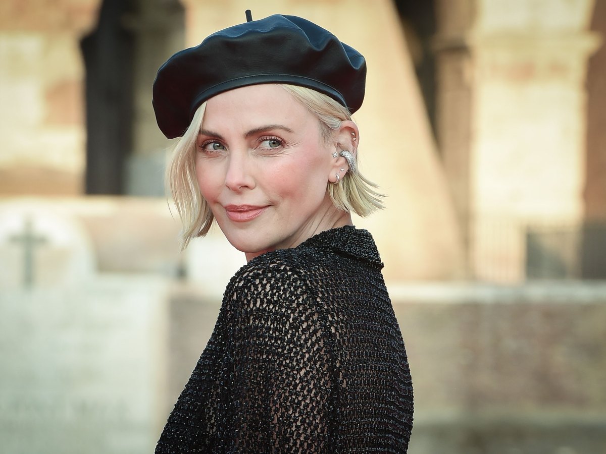 Charlize Theron hat eine V-Figur und trägt hier ein schwarzes Shirt.