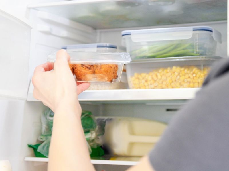 Ein Mann sortiert Plastikdosen mit Gemüse in den Kühlschrank