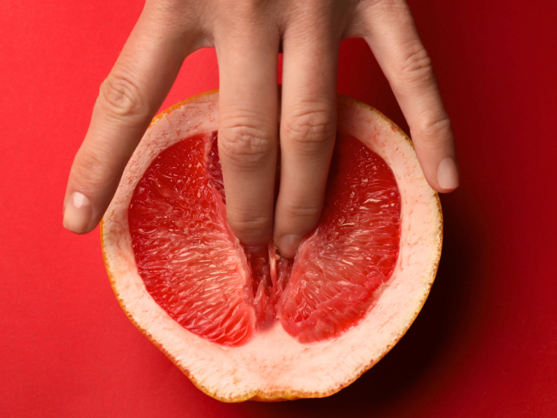 Frau drückt zwei Finger in eine Grapefruit.