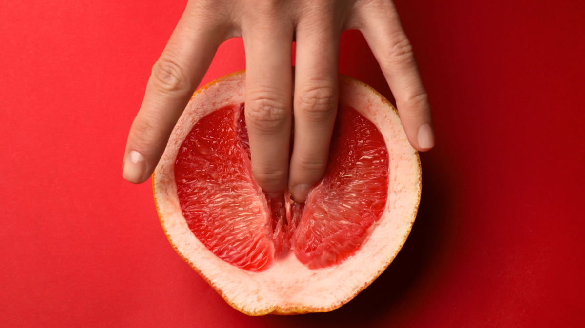 Frau drückt zwei Finger in eine Grapefruit.