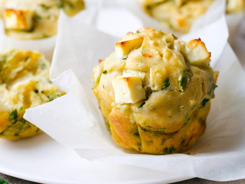 Herzhafte Muffins mit Feta und Rucola auf weißem Teller.