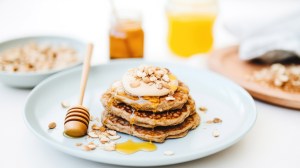 Haferflocken Pancakes auf einem weißen Teller mit Honig und Joghurt obendrauf.