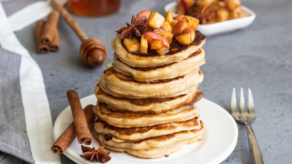 Pancakes auf einem weißen Teller mit Apfelkompott obendrauf.