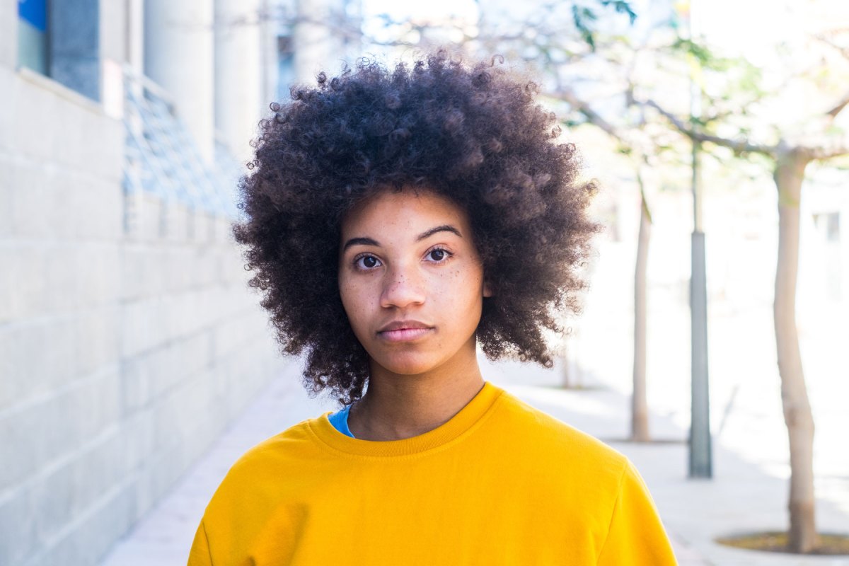 Frau mit Afro mit gelbem Pullover