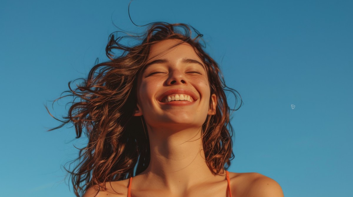 Frau mit blauem Himmel im Hintergrund, die glücklich lächelt